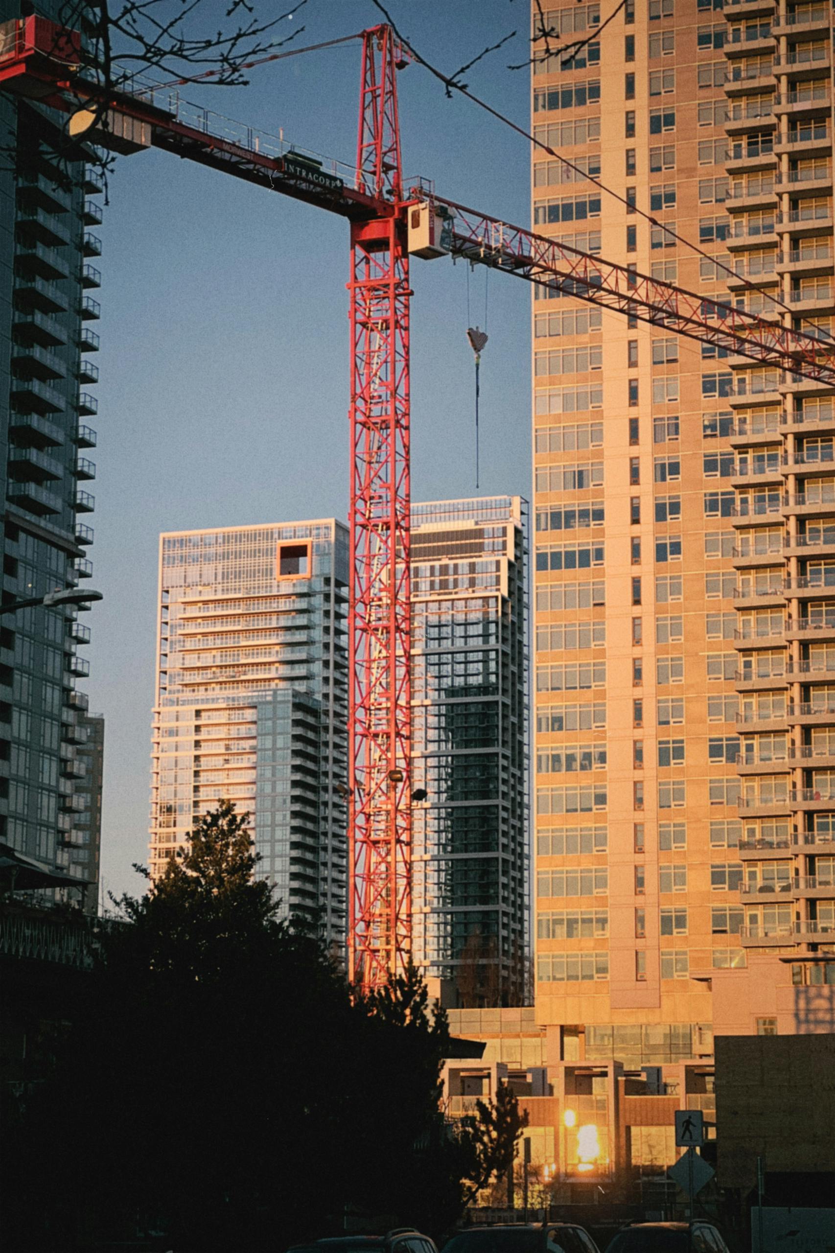 Crane and highrise buildings under construction during sunset in the city.